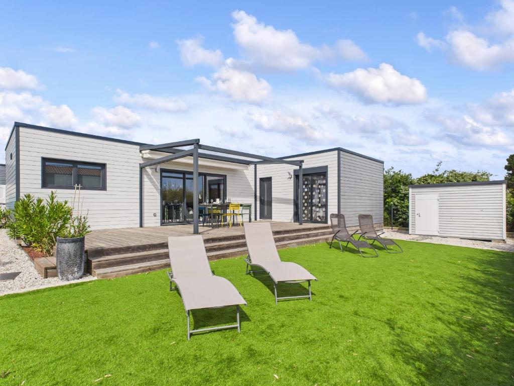 une maison modulaire avec des chaises et une pelouse dans l'établissement Chalet pour 6 - Piscine chauffée - Terrasse, à Bretignolles-sur-Mer