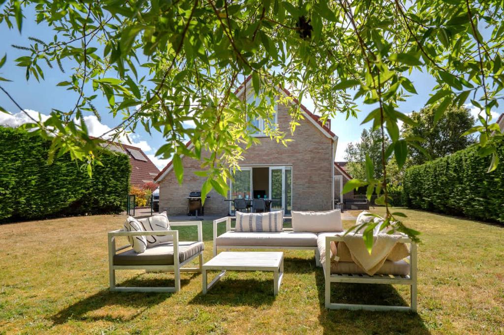 ブレスケンスにあるHello Zeeland - Vakantiehuis Zwin 112の木の下にソファとテーブルのあるパティオ