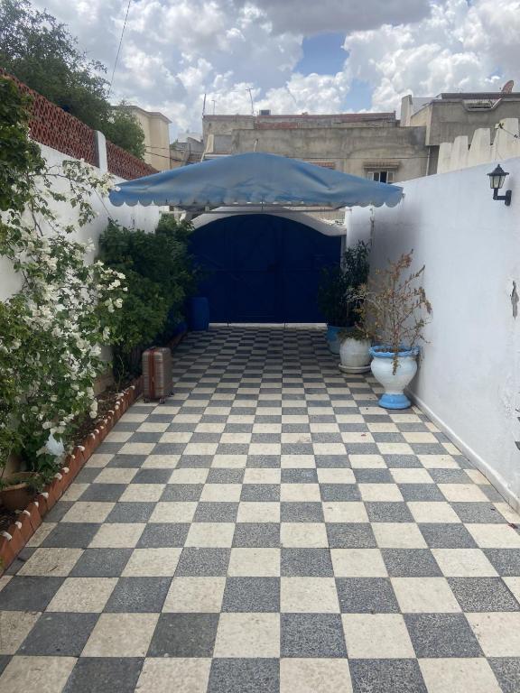 a garage with a blue umbrella on a checkered floor at Maison El Omrane 2 in Milletville