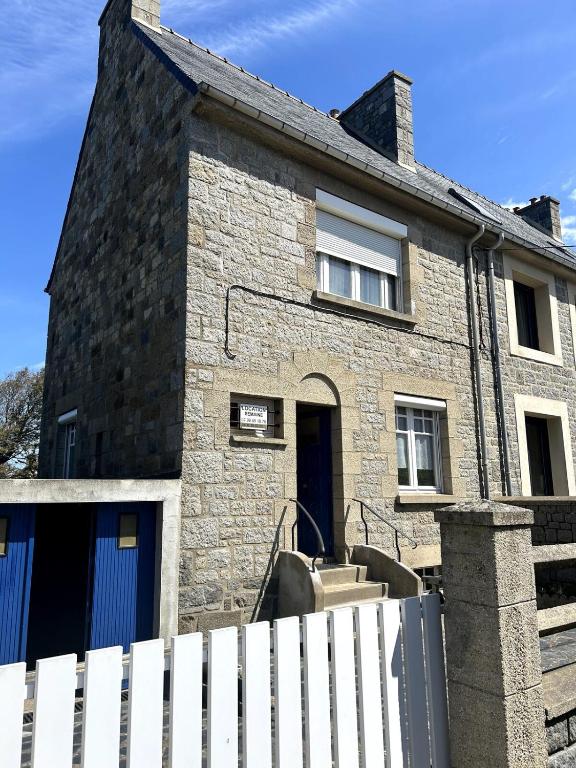 une maison en briques avec une clôture blanche devant elle dans l'établissement Petit Kennedy Maison 4 personnes Rochebonne, à Saint-Malo