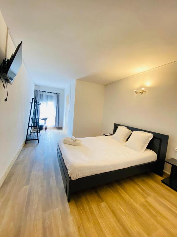a bedroom with a large bed with a wooden floor at Canaan Hôtel Antsirabe in Antsirabe