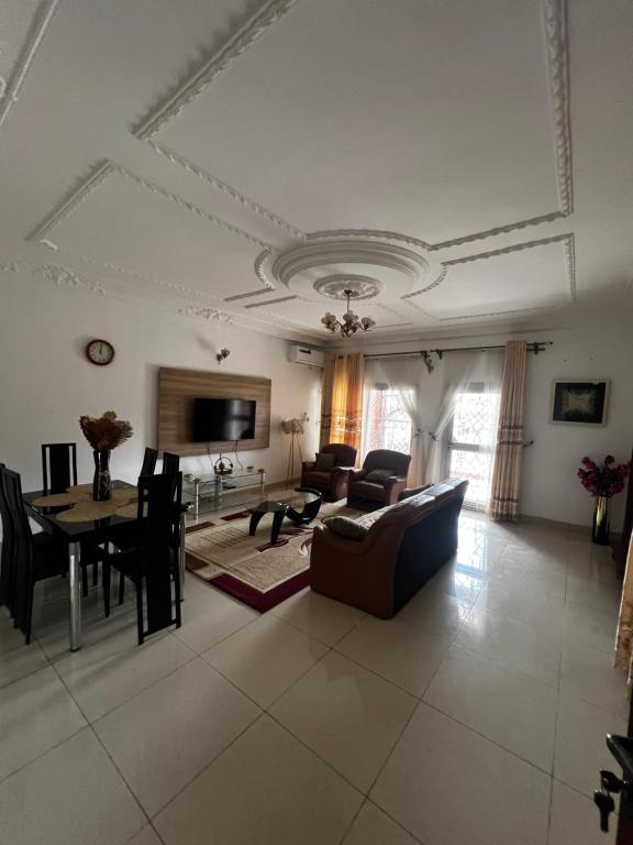 a living room with a couch and a table at Appartement Jardin Dachille - Résidence Shalom Bonamoussadi avec Wifi, Clim, Parking, Gardien 24h in Douala
