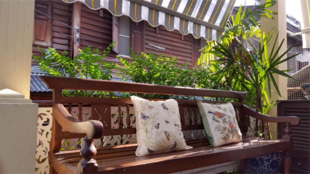 a wooden bench with two pillows sitting on it at Villa Mungkala in Bangkok