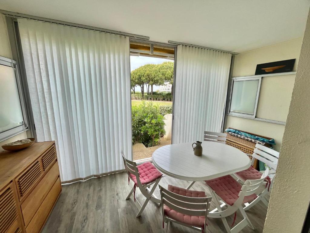 une salle à manger avec une table et des chaises blanches dans l'établissement Port Camargue : Appartement 4 personnes, plage & jardin, parking privatif - FR-1-716-87, au Grau-du-Roi