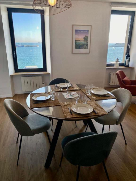 une table de salle à manger avec des chaises et une grande fenêtre dans l'établissement L'Amiral - vue mer sur le port, à Roscoff