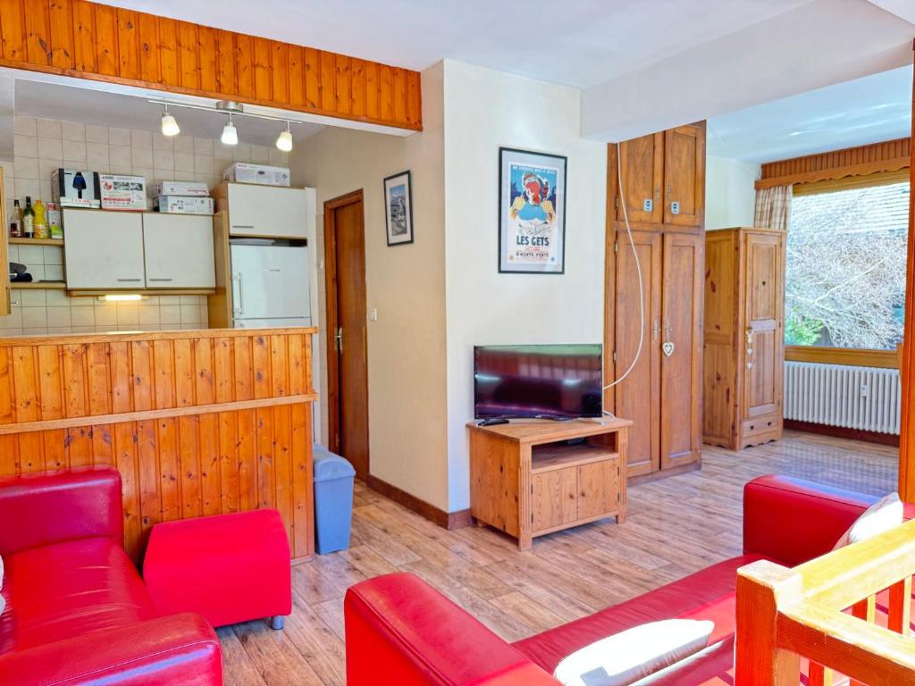 d'un salon doté d'un mobilier rouge et d'une télévision. dans l'établissement Appartement cosy 8 pers avec terrasse, proche des pistes, Les Gets - FR-1-623-368, aux Gets