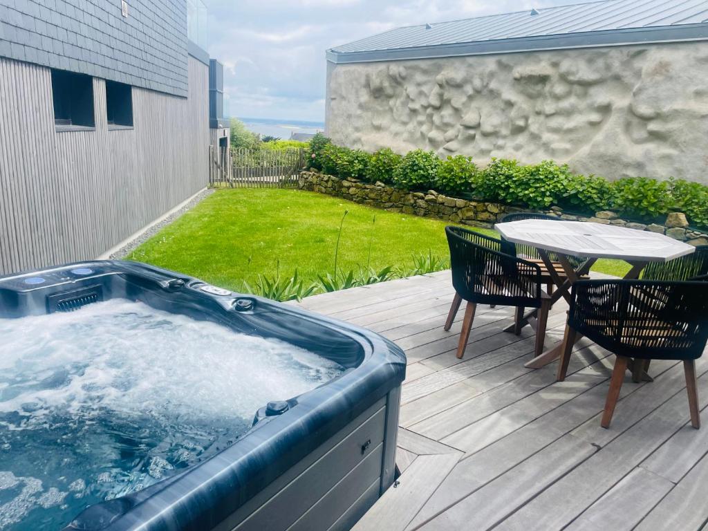 wanna z hydromasażem na tarasie ze stołem i krzesłami w obiekcie Ty Dag - Petite Terre vue mer, spa, plage à 300m w mieście Roscoff