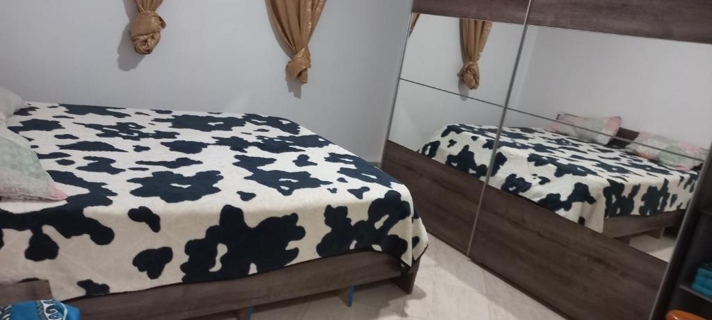 een slaapkamer met een zwart-wit bed en een spiegel bij appartement T3 équipe in Matriouene