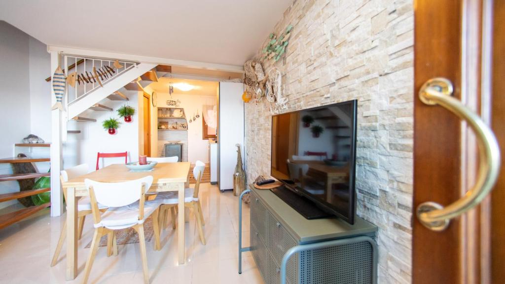 a living room with a dining room table and a stone wall at Dimora Rubino - Isola di Pellestrina Ve in Pellestrina