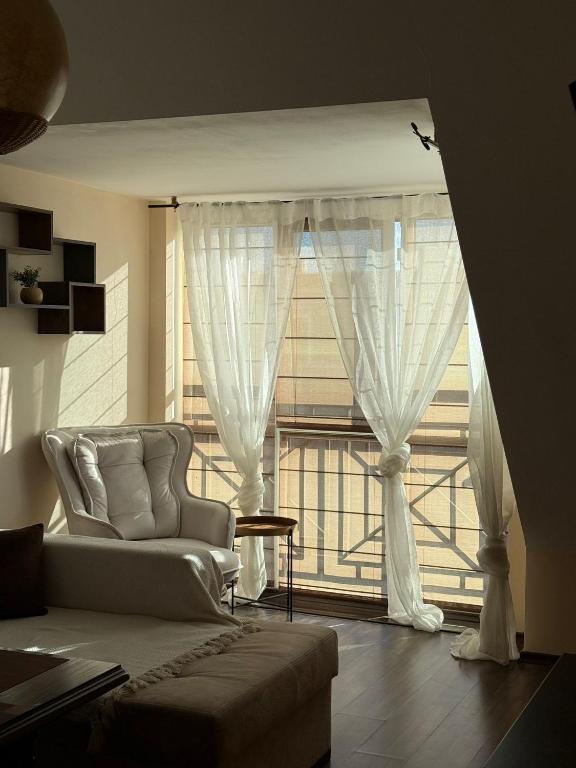a living room with a couch and a large window at Home by the Sea MAIN STREET and POOL in Burgas