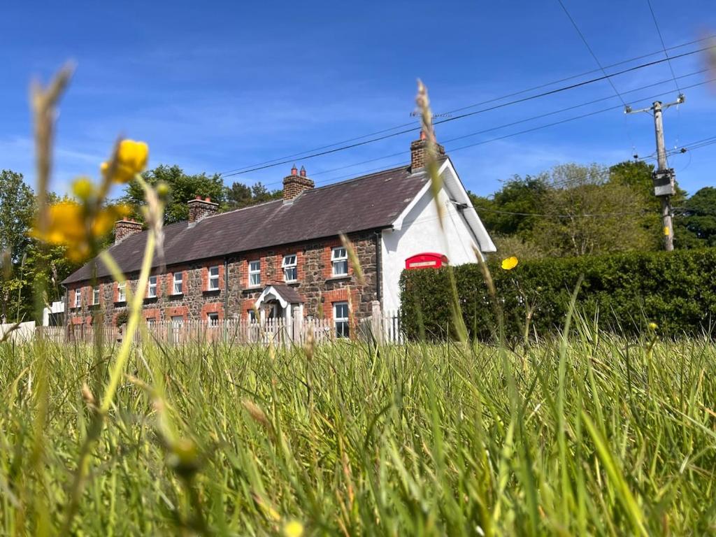 ein rot-weißes Haus mit einer Wiese in der Unterkunft Fiddlers Cottage in Springmount