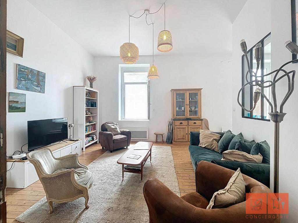 een woonkamer met een groene bank en een tv bij La parenthèse in Wimereux