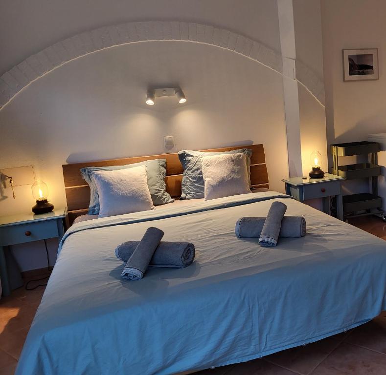 a large white bed with two blue pillows on it at Casa Monki in Raposeira