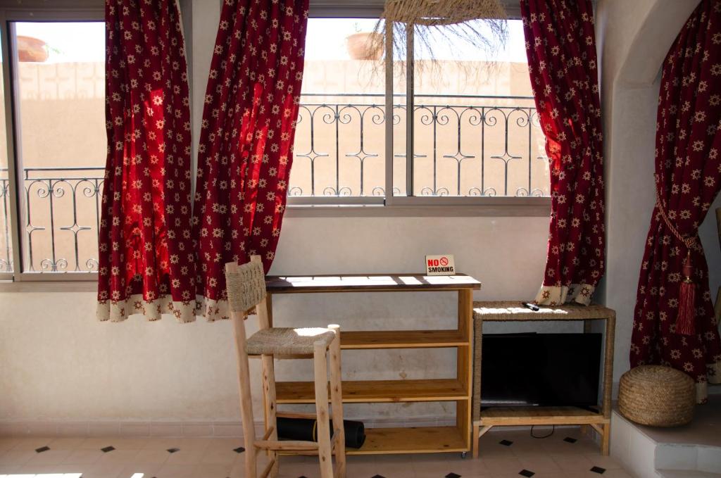 a room with red curtains and a desk and a window at SurfAppart Morocco in Tamraght Ouzdar