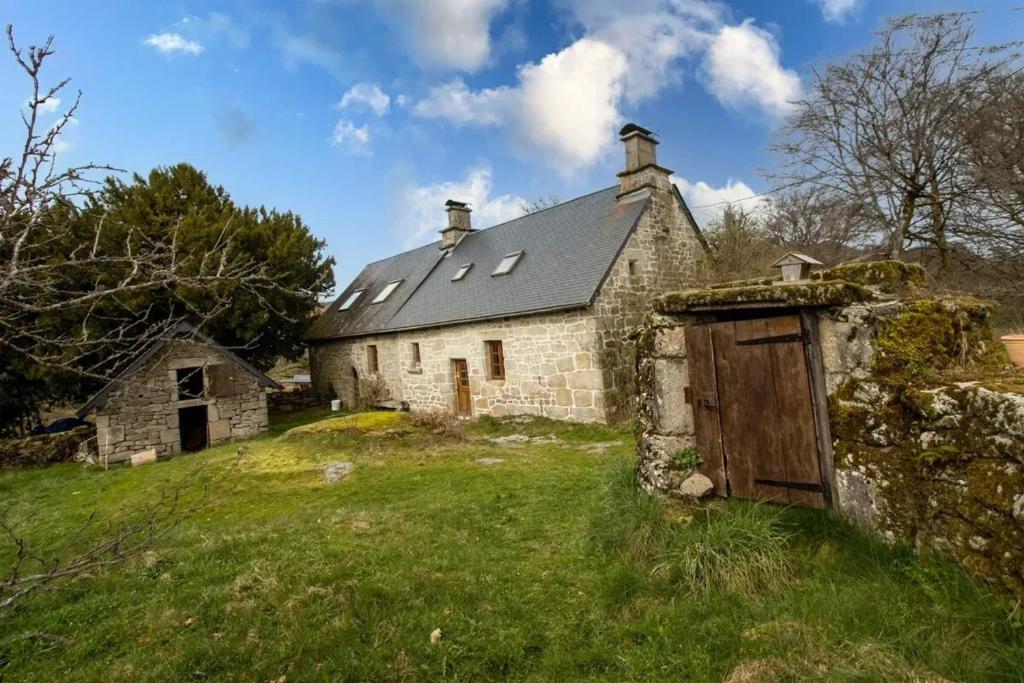 un ancien bâtiment en pierre avec une porte dans un champ dans l'établissement Maison en granite typique à Chaumeil avec cheminée, à Chaumeil