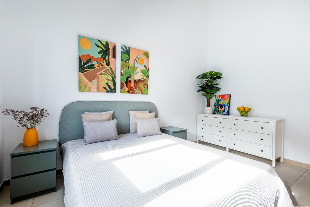 a bedroom with a bed with two dressers and two paintings at Playa de San Juan - Santa Martha duplex in Playa de San Juan