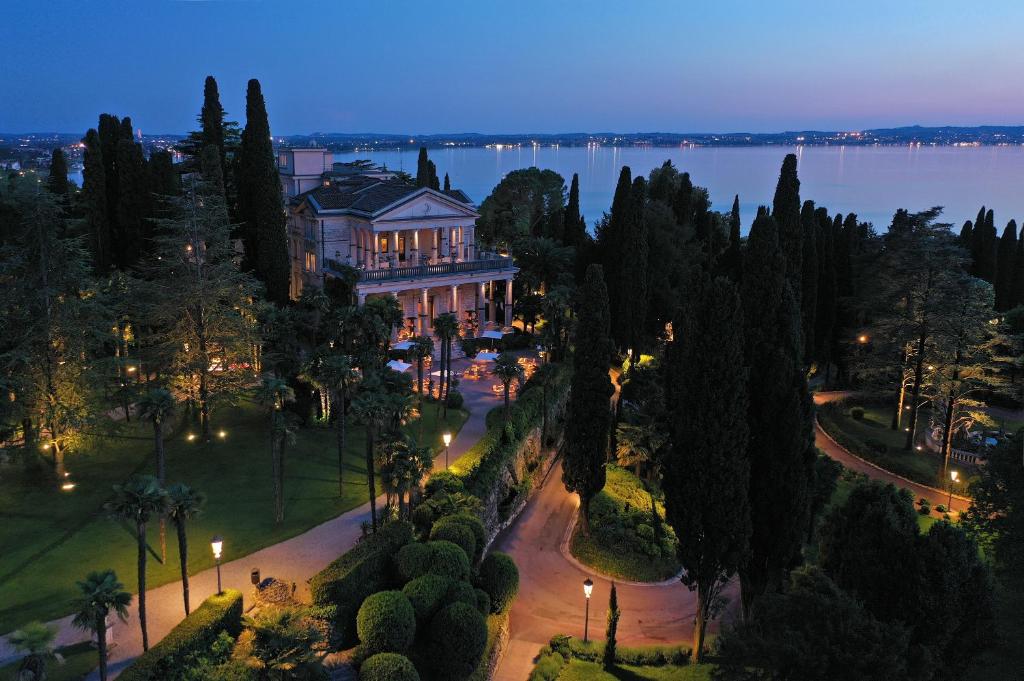 a large house on a street in front of the water at Villa Cortine Palace Relais Chateaux in Sirmione