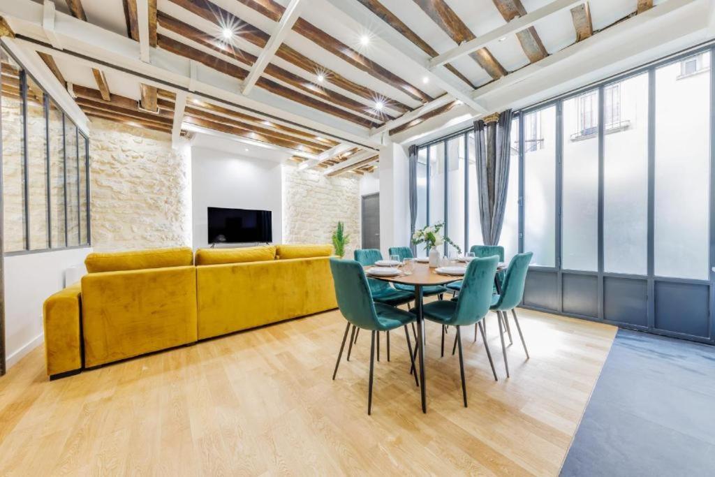 a living room with a yellow couch and a table and chairs at Bridgestreet Le Marais - les halles - Republique in Paris