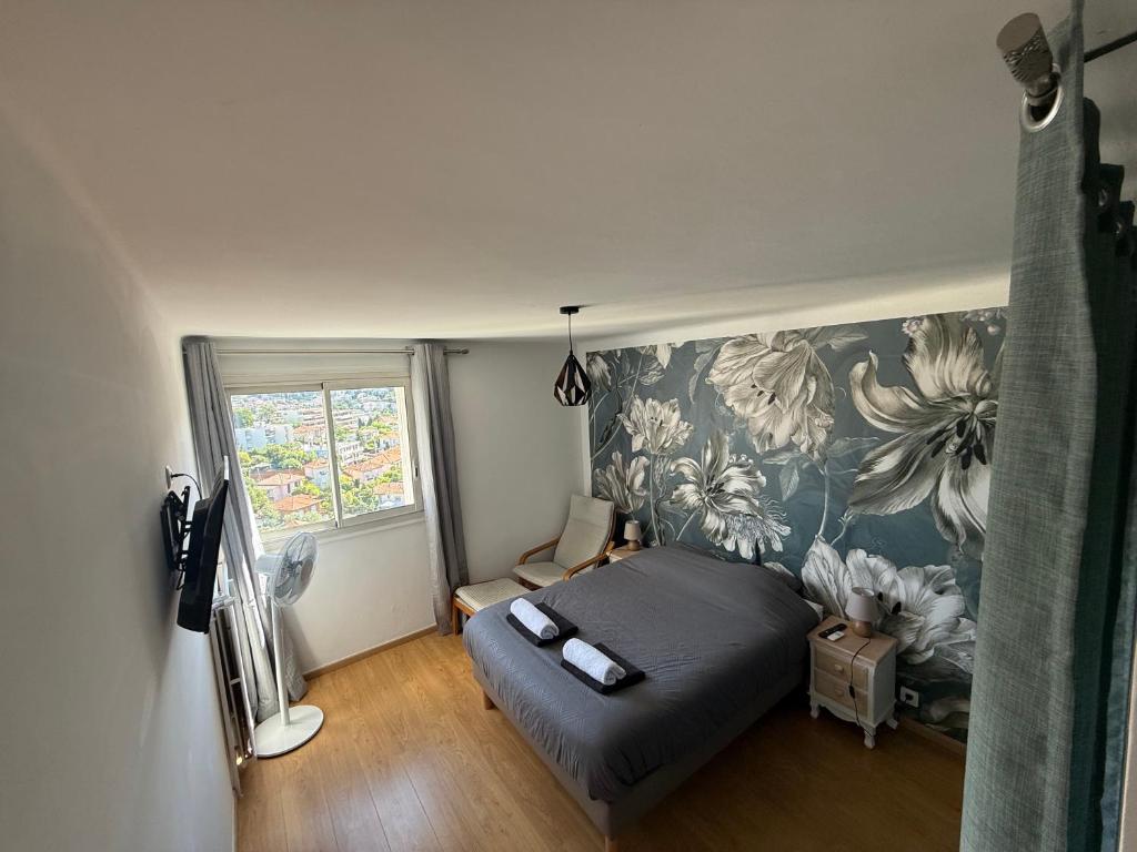 - une chambre avec un lit et un mur à motifs floraux dans l'établissement Appartement vue sur collines de Cannes, au Cannet