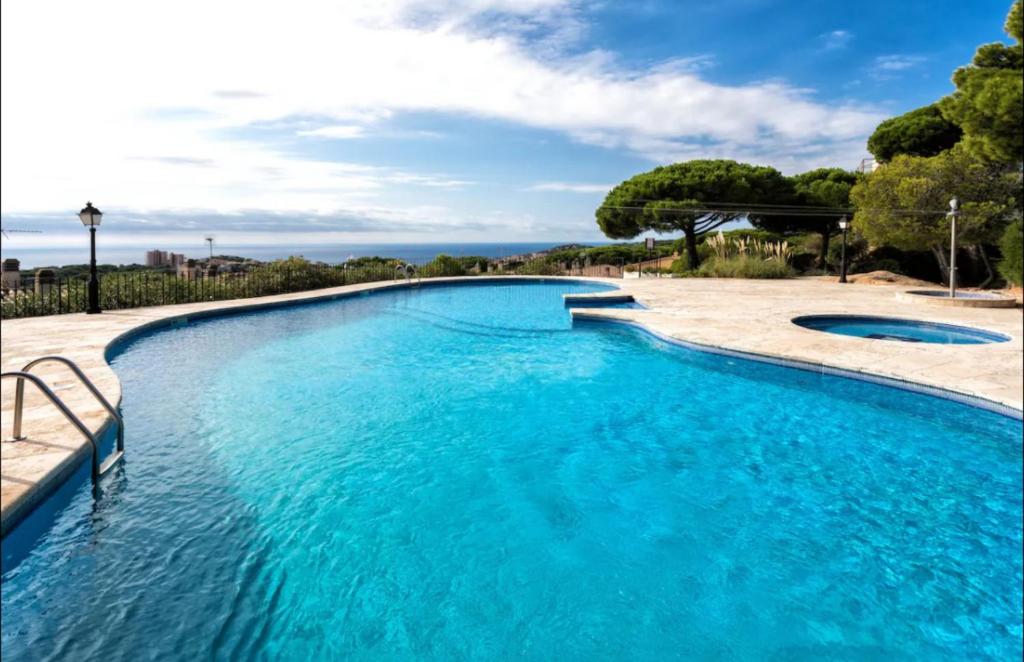 a large swimming pool with blue water at Hauzify I Apartament Grumet in Sant Feliu de Guixols