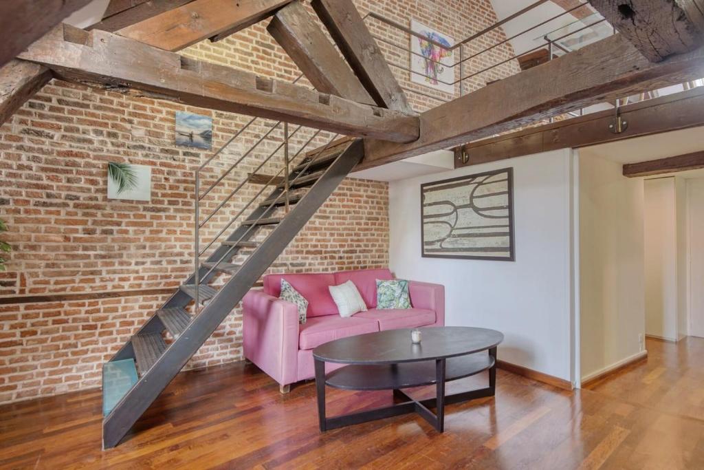 - un salon avec un canapé rose et un mur en briques dans l'établissement Nice atypical apartment, Vieux Lille, à Lille