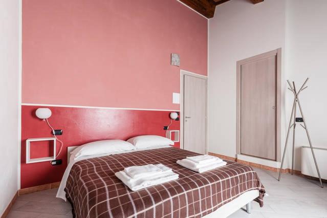 - une chambre avec un grand lit et un mur rouge dans l'établissement B&B Bianchi 64, à Pise