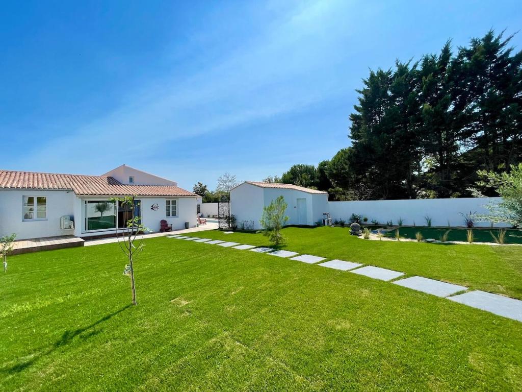 une cour avec une maison blanche et une pelouse verte dans l'établissement 900-D La Chaumillonière - Modernity, comfort and pool, au Bois-Plage-en-Ré