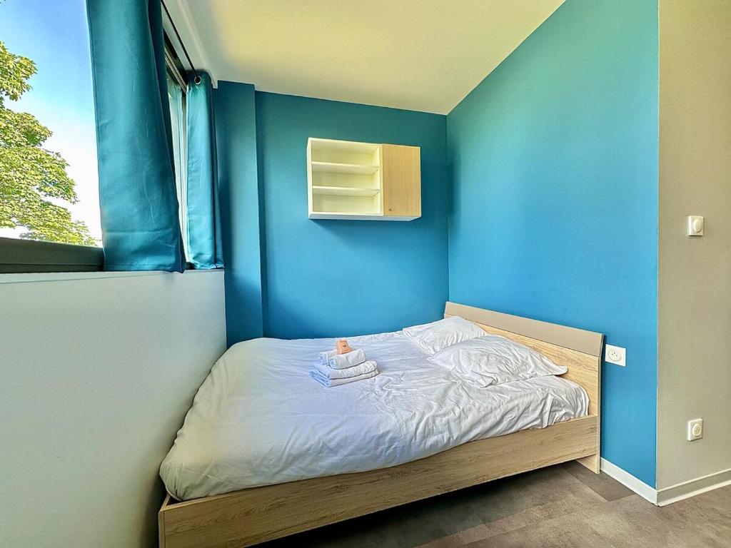 ein kleines Bett in einem Zimmer mit einer blauen Wand in der Unterkunft Studio 63 Rénové et Équipé - Nancy Brabois proche CHRU,CESI,FAC in Vandoeuvre-lès-Nancy