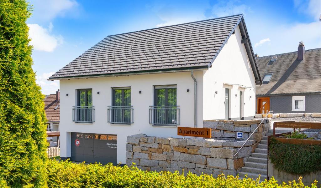 a white house with a stone wall at Apartment 1 - Schmiedefeld - klein und fein in Schmiedefeld am Rennsteig