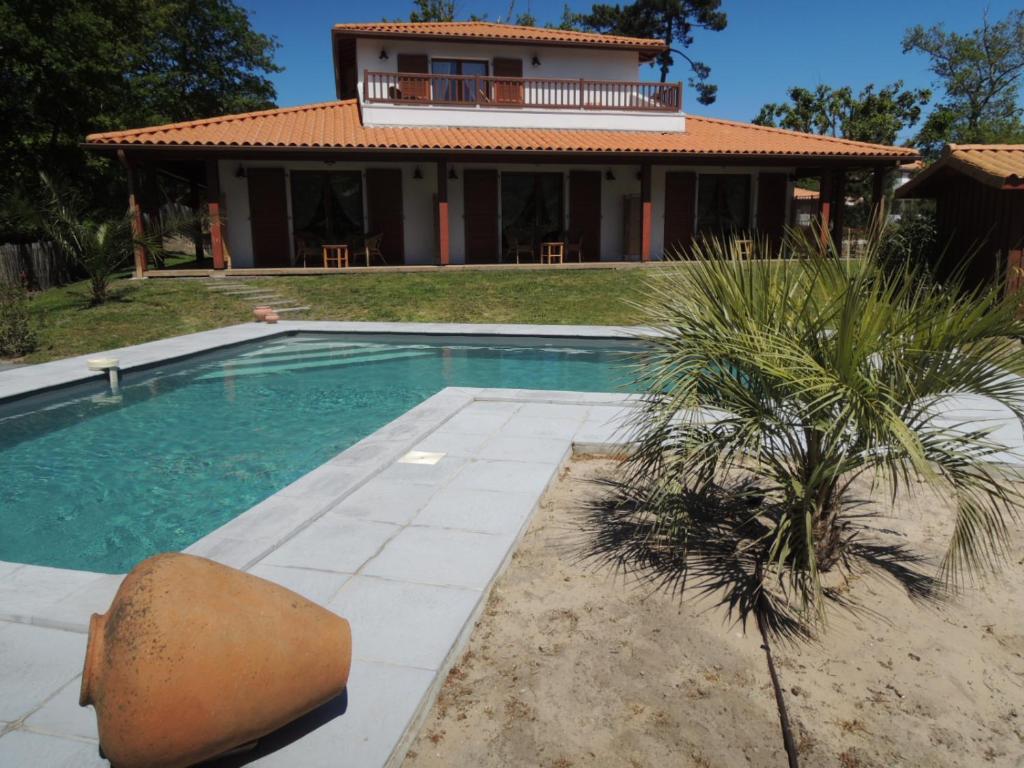 uma casa com piscina em frente a uma casa em Via Bahia - Maison d'hôtes em Biscarrosse