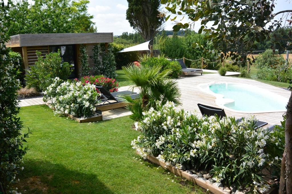 a garden with a swimming pool and some flowers at Timazen Lodges Agen Sud in Aubiac