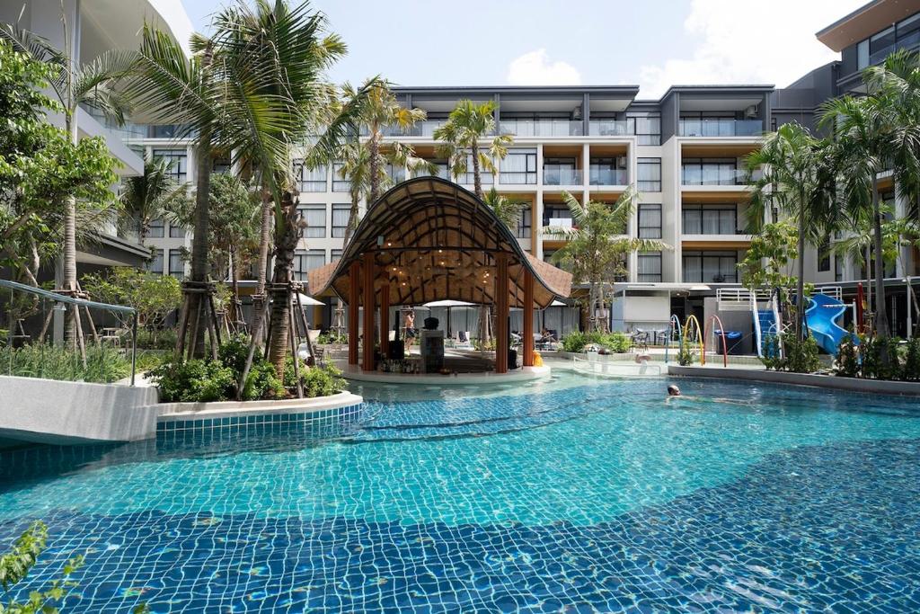 - une piscine avec un kiosque en face d'un bâtiment dans l'établissement Stylish Beachfront 2BR Flat, à Nai Thon Beach