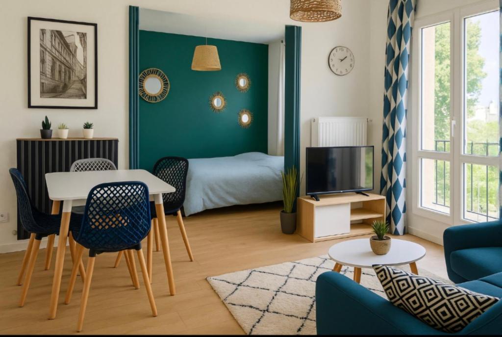 a living room with a bed and a table and chairs at Appartement Spacieux & Parking in Caen