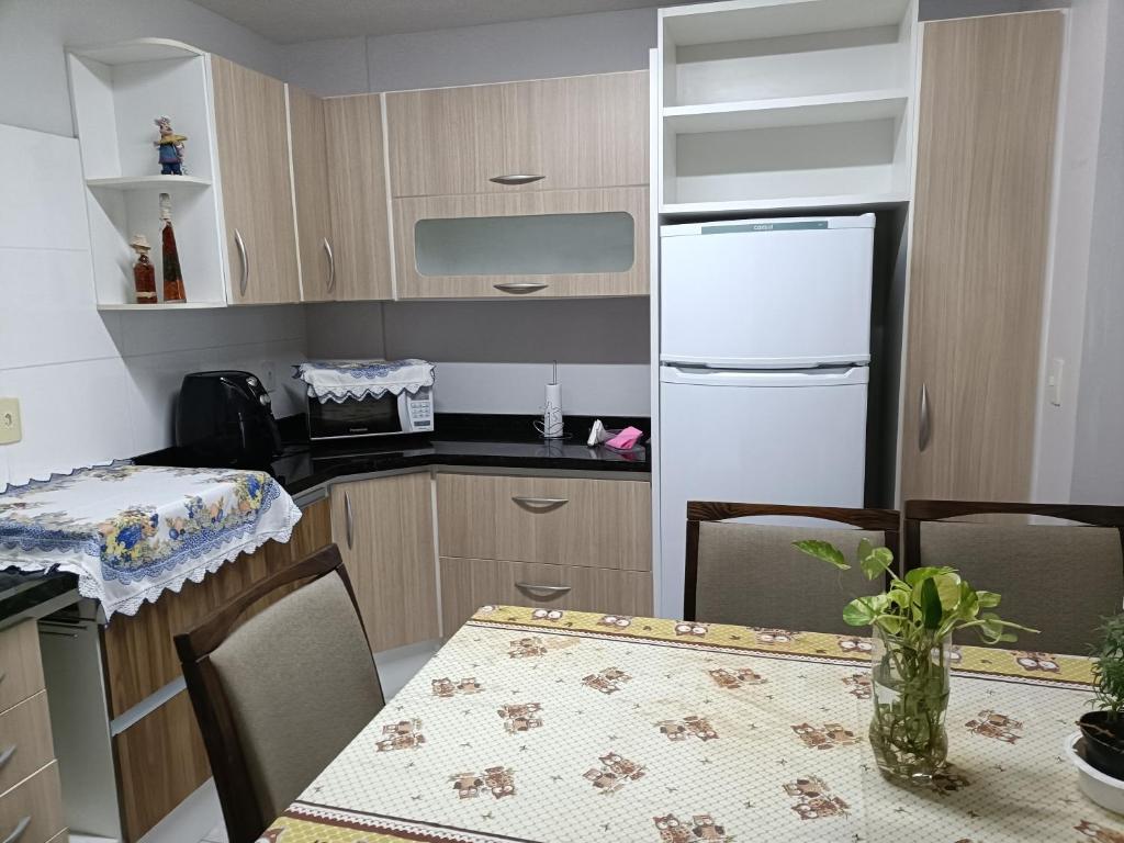 une cuisine avec une table et un réfrigérateur blanc dans l'établissement Apartamento 301 - 3 andar de frente para o mar, à São Francisco do Sul