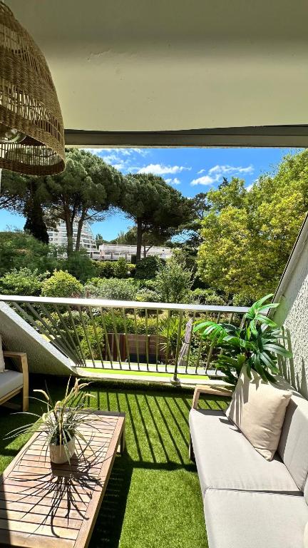 d'un balcon avec un canapé blanc et une table. dans l'établissement LE BOHÈME - balcon vue jardin - clim - place de parking - wifi - 5min plage, à La Grande Motte