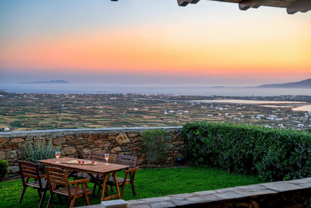 a table and chairs with a sunset in the background at Villa 7Days I Relax with Private Jacuzzi & SeaView in Agkidia