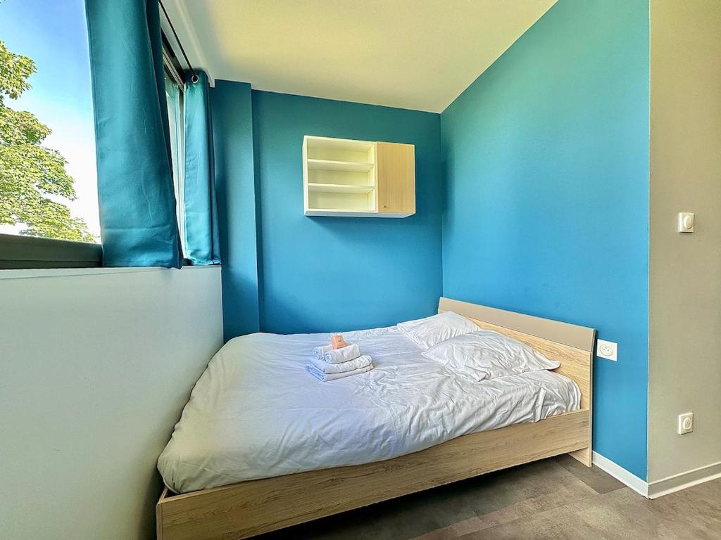 ein kleines Bett in einem Zimmer mit einer blauen Wand in der Unterkunft Studio 65 Rénové et Équipé - Nancy Brabois proche CHRU,CESI,FAC in Vandoeuvre-lès-Nancy