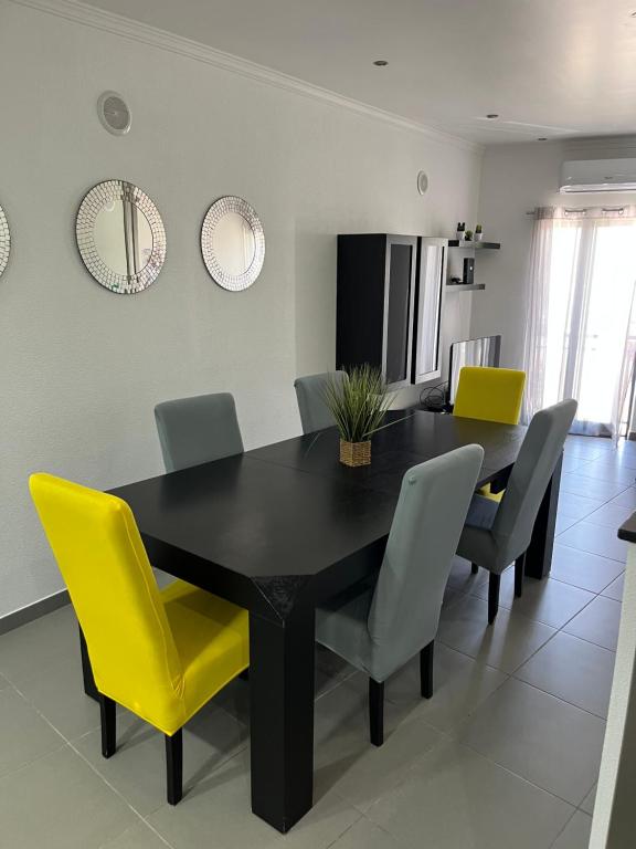 a dining room with a black table and yellow chairs at AL Manas Pereira in Castro Marim