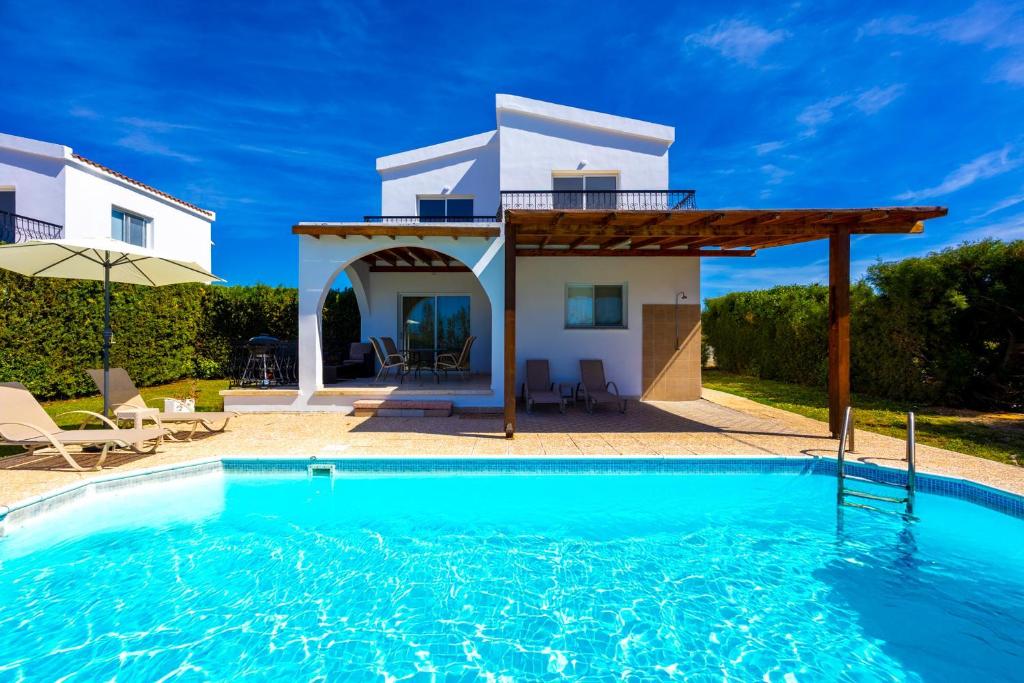 a villa with a swimming pool in front of a house at Villa Christina in Argaka