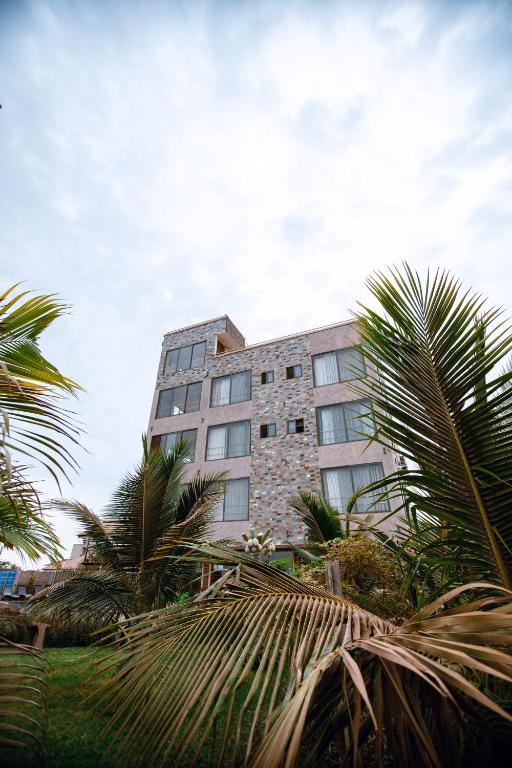 Plus 33 Hotel في Sakumona: مبنى شاهق تحيط به أشجار النخيل