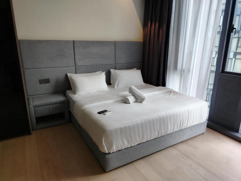 a bed with white sheets and pillows in a room at KLCC by Star Residences in Kuala Lumpur