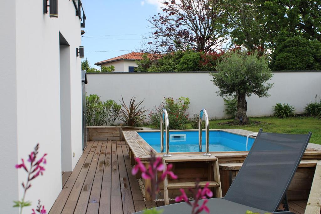 une cour arrière avec une piscine et une terrasse en bois dans l'établissement Maison proche plages, au calme, piscine et parking, à Anglet