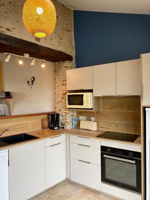 une cuisine avec des armoires blanches et un micro-ondes dans l'établissement Gîte Le Petit Ermitage Ste Cécile Vendée, à Collonges-au-Mont-dʼOr