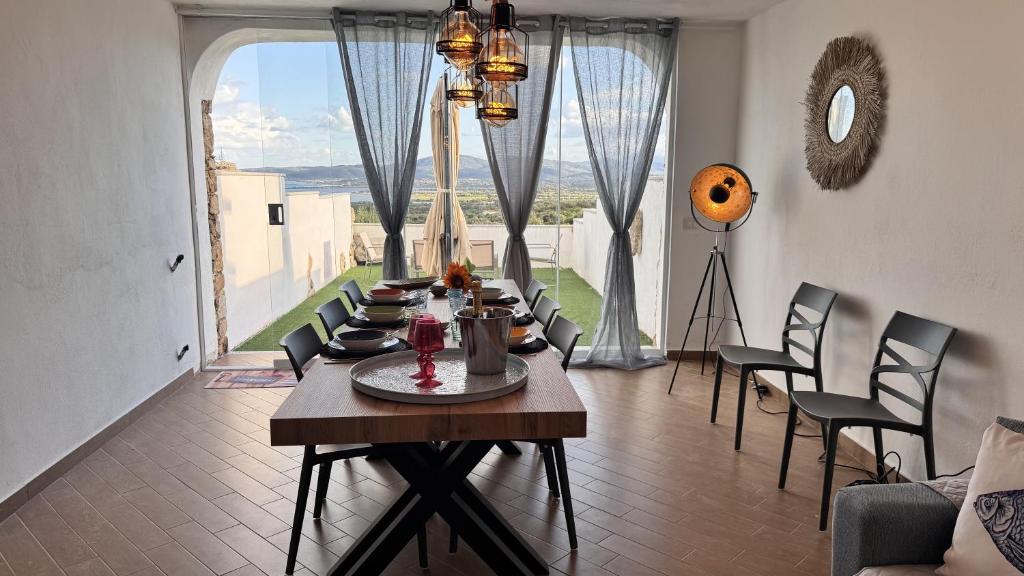 een eetkamer met een tafel en stoelen en een groot raam bij La casa delle Stelle by Ca-Sa Check in San Teodoro