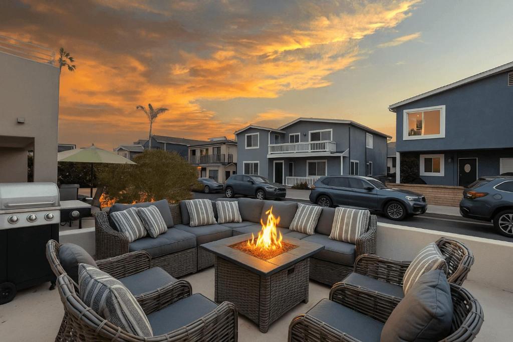 a patio with couches and a firepit with a fire burns at Sandy by AvantStay Oceanview Steps to Beach Patio w Fire Pit Dining Area in Newport Beach