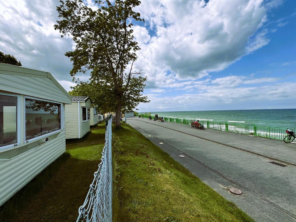 a fence next to a road next to the ocean at Alex Domki Angielskie Taras Widokowy in Rewal