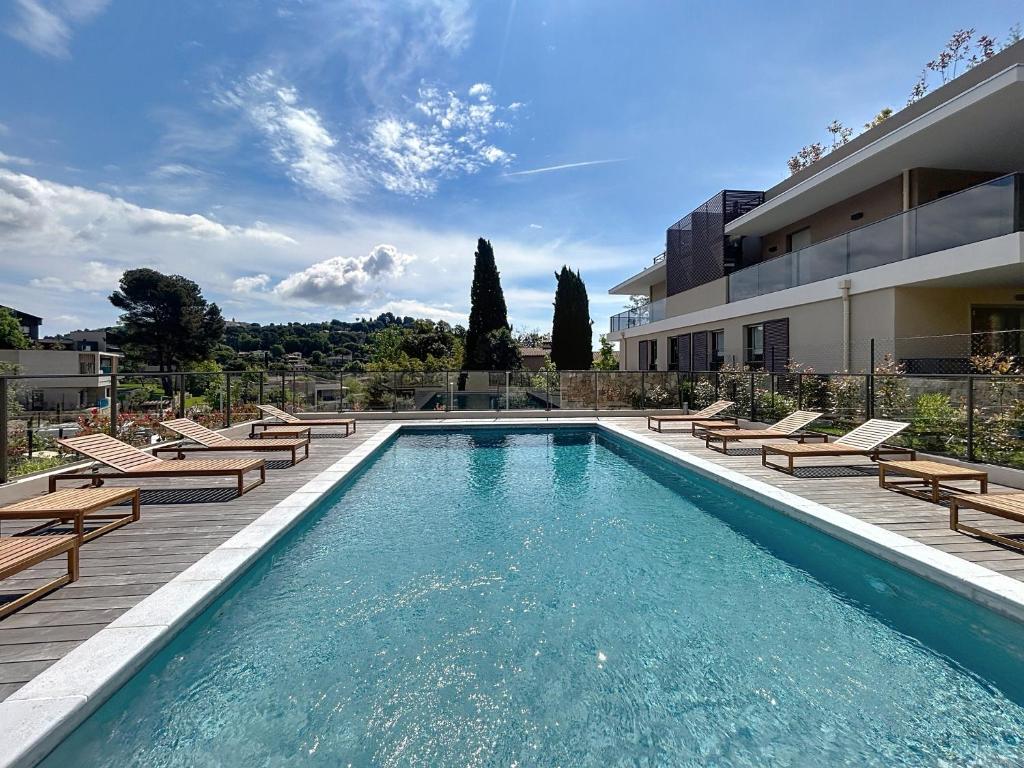 une piscine avec des chaises et un bâtiment dans l'établissement Juyette, à Mougins