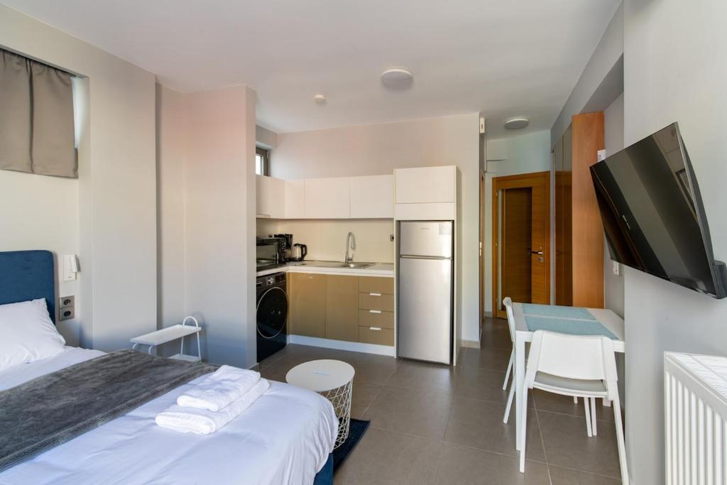 a bedroom with a bed and a table and a kitchen at Odeio UpTown urban stay studio in Patra