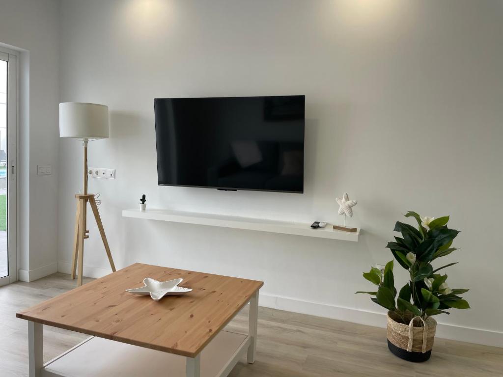 a living room with a table and a tv on a wall at Island Home Fuerteventura in Corralejo