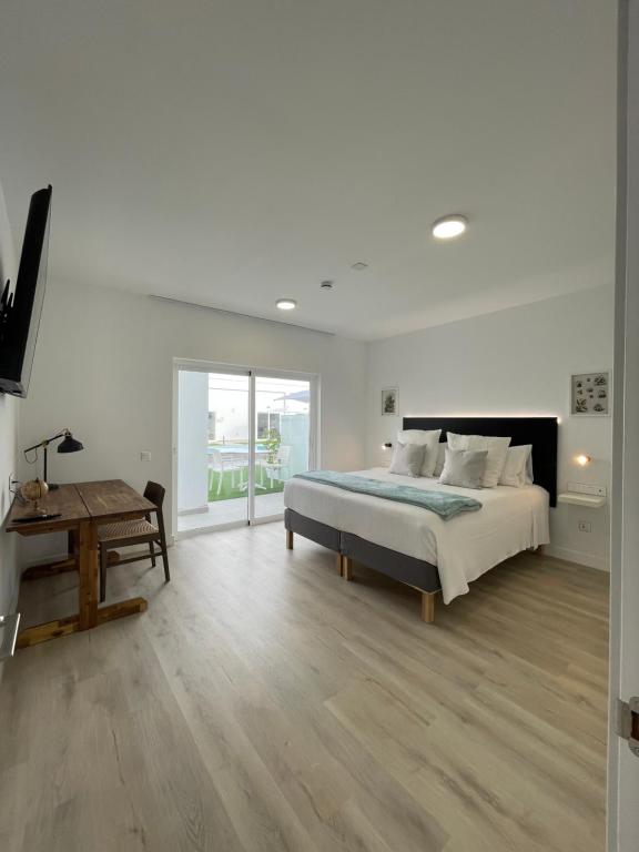 a white bedroom with a bed and a table at Island Home Fuerteventura in Corralejo